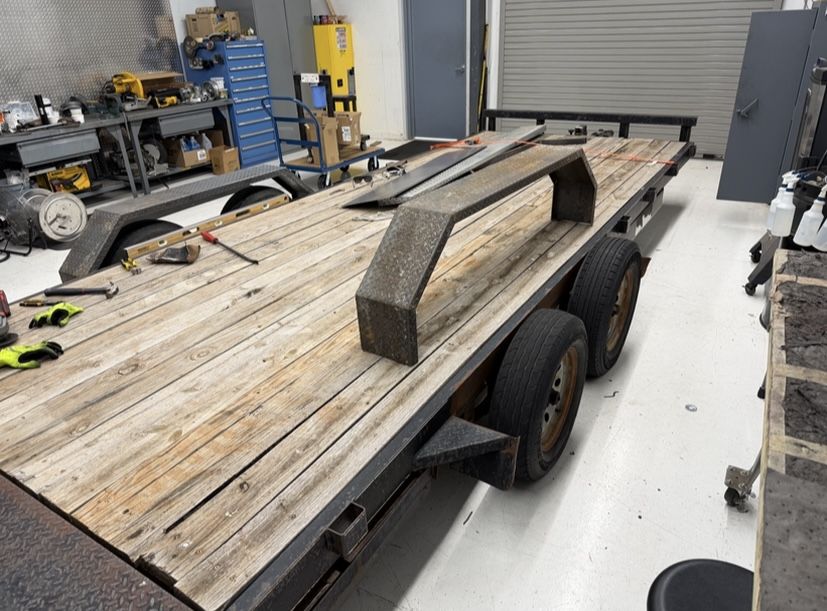 Two drive over trailer fenders laid out on a flatbed trailer deck during fitting in a fabrication shop